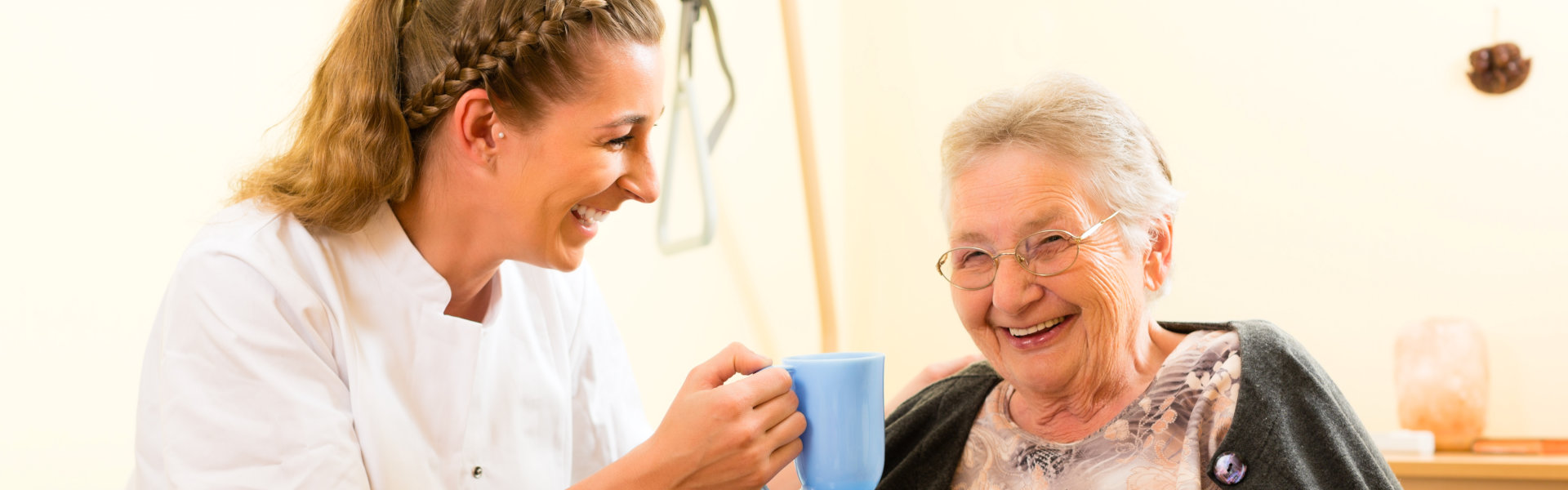 Lady giving grandma a cup of drink